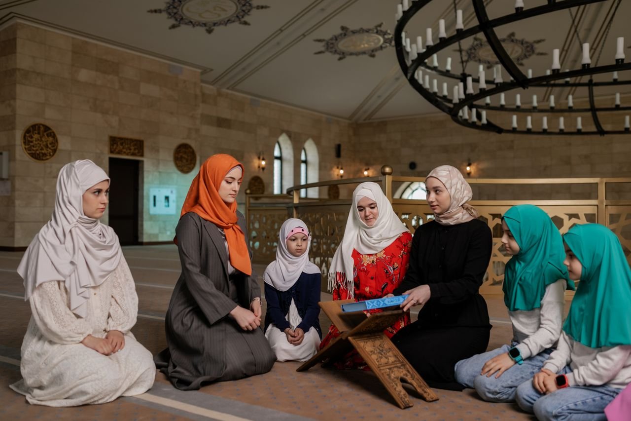 Islamic Studies for Kids Course Women and children wearing headscarves praying inside a mosque for religious gathering.